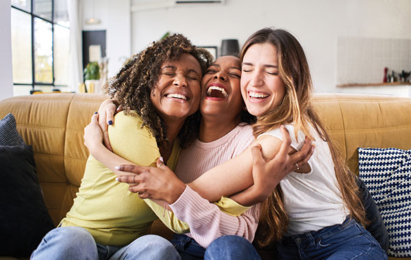Three women friends hugging each other and smiling